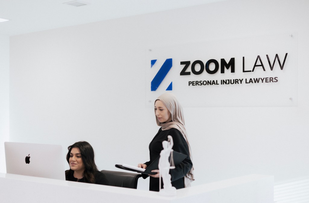 The Zoom Law team at the front desk beneath the Zoom Law signage